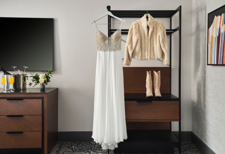 Bridal gown and winter jacket displayed in a Hotel Alpenrock suite, styled for a mountain wedding.