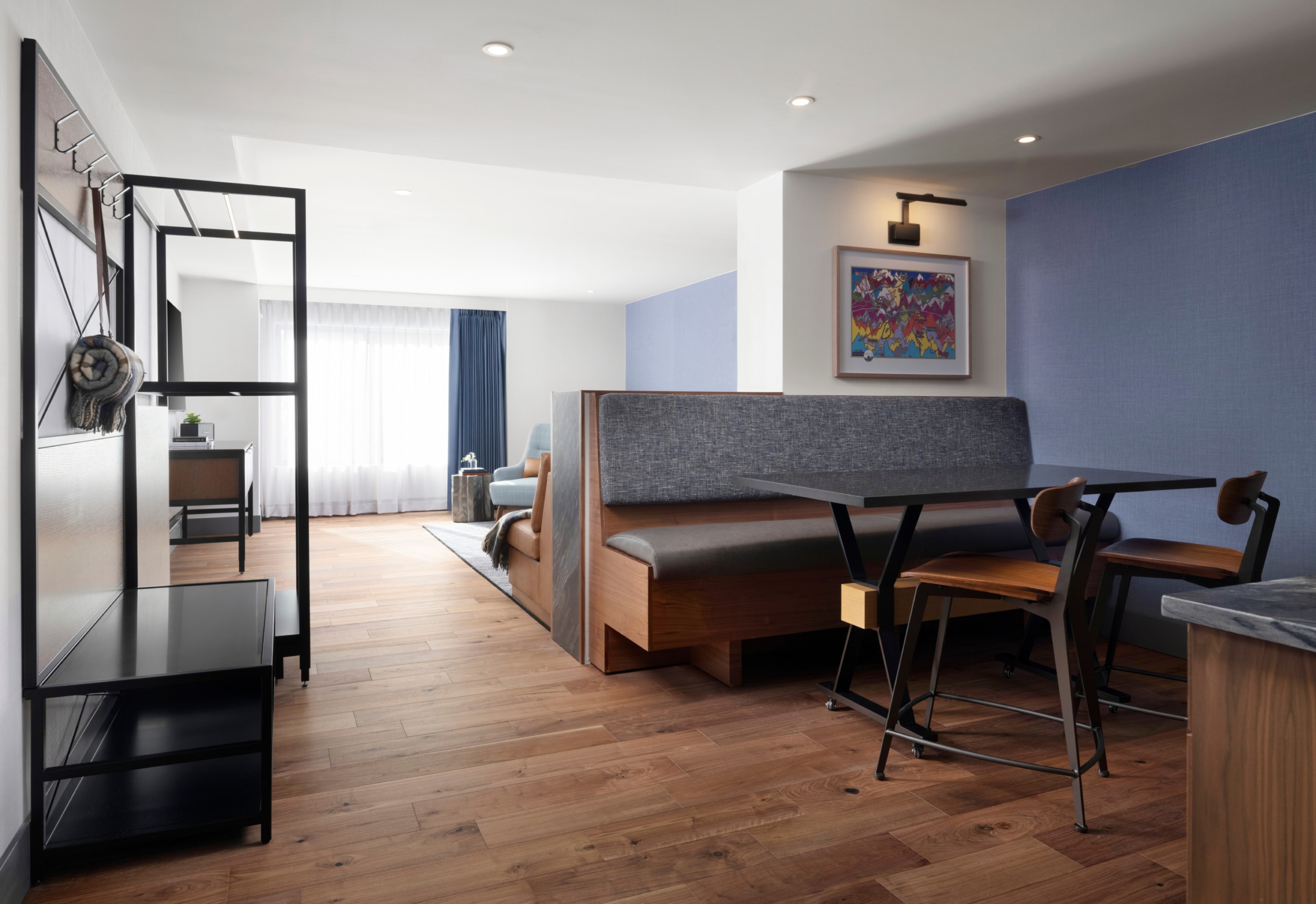 Open one-bedroom suite at Hotel Alpenrock with dining booth, wood floors, and living area visible in the background.