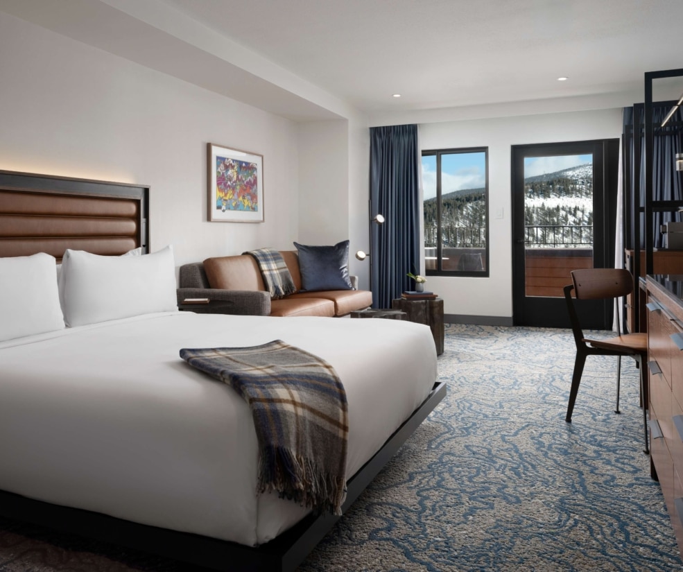 Accessible king guest room at Hotel Alpenrock with a spacious layout, king bed, seating area, work desk, and balcony doors opening to mountain views.