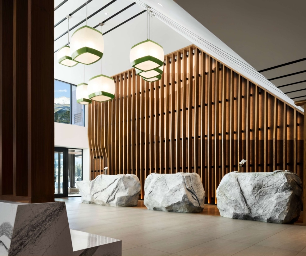 Stone front desk and pendant lighting in the Hotel Alpenrock lobby.