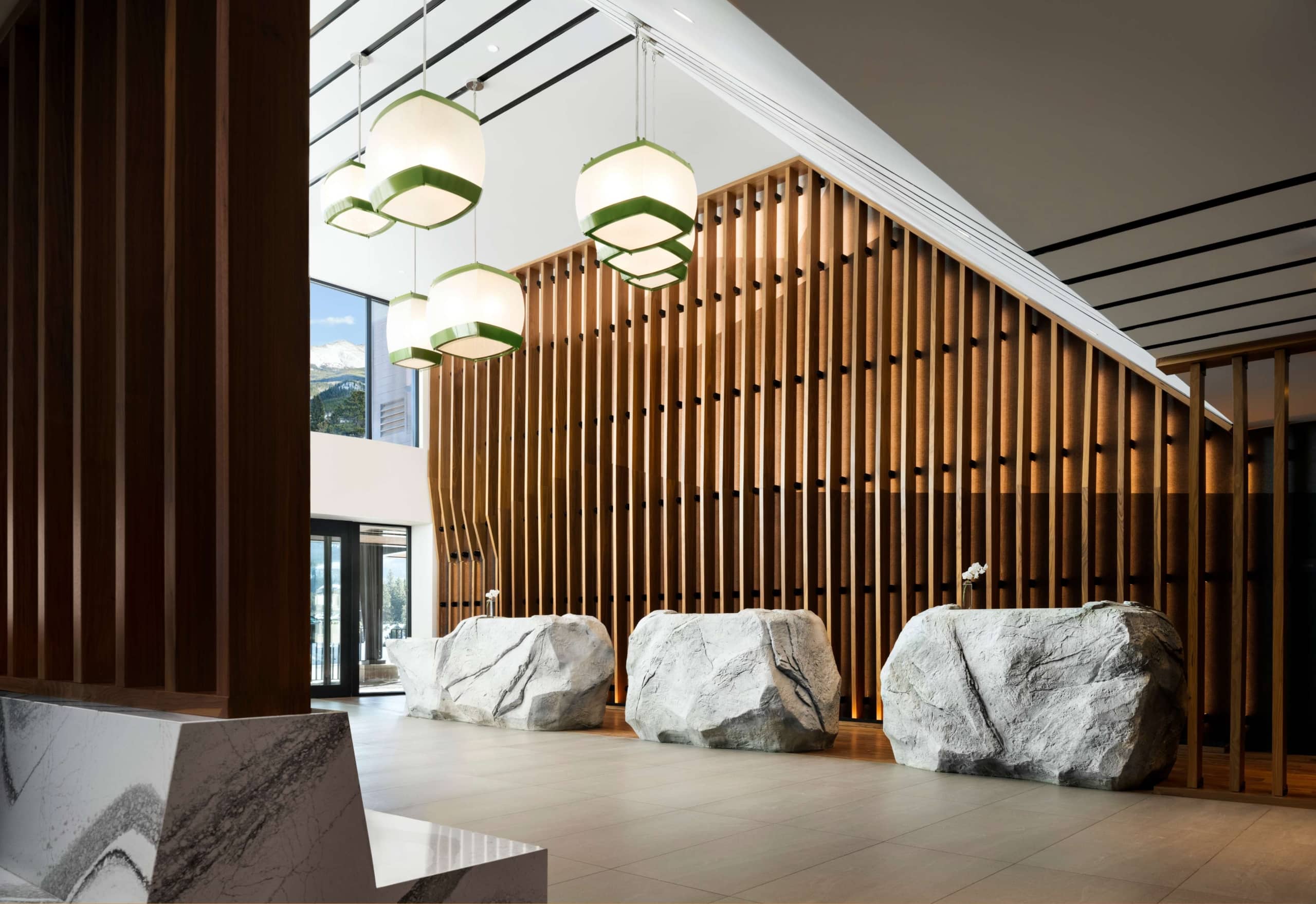 Stone front desk and pendant lighting in the Hotel Alpenrock lobby.