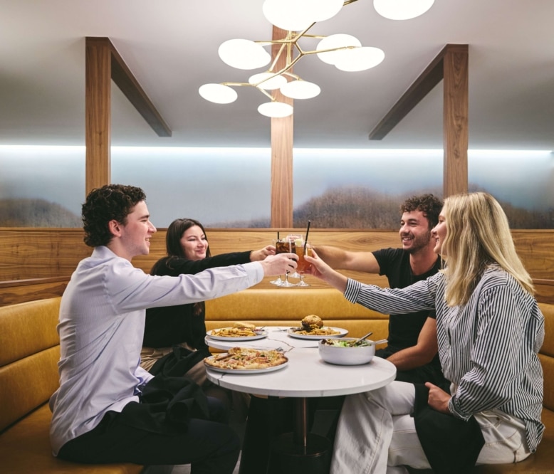 Guests enjoying a relaxed meal and drinks inside Hotel Alpenrock’s modern dining lounge with warm wood finishes and soft lighting.