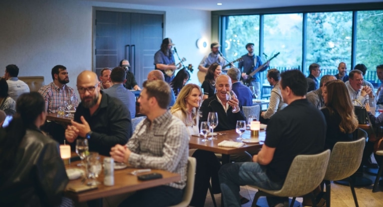 Guests laughing and enjoying dinner at Hotel Alpenrock, seated around a warmly lit table inside the restaurant.