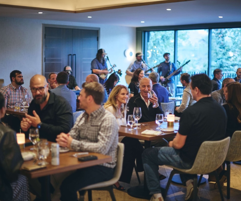 Guests laughing and enjoying dinner at Hotel Alpenrock, seated around a warmly lit table inside the restaurant.