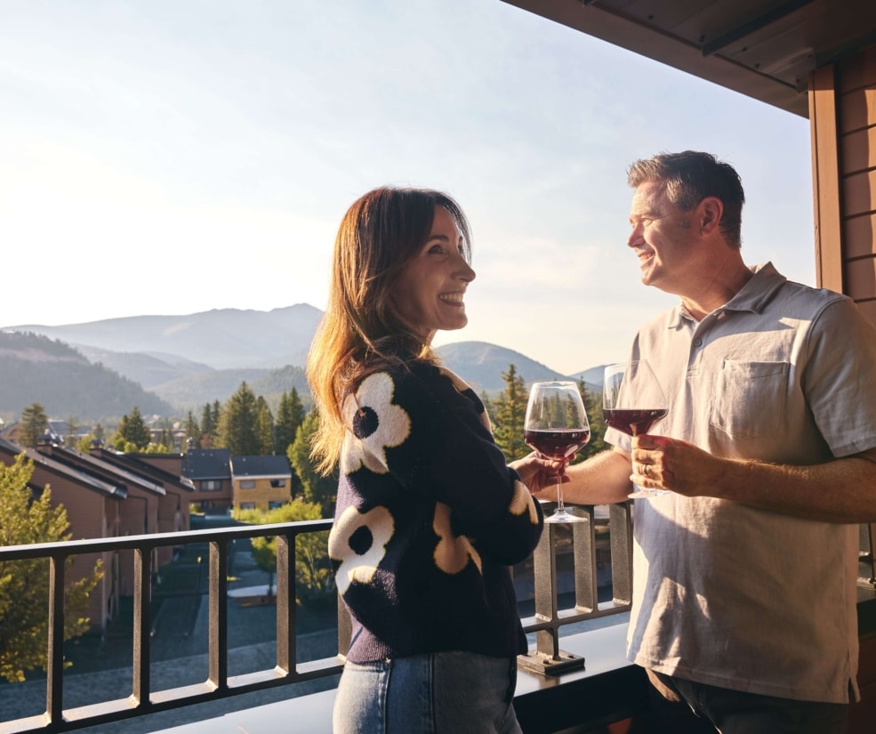 Couple enjoying wine on a guest room balcony with mountain views at Hotel Alpenrock.