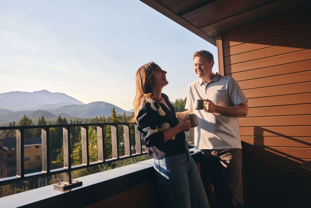 Couple enjoying coffee on a guest room balcony with mountain views at Hotel Alpenrock.