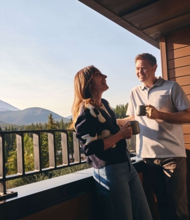 Couple enjoying coffee on a guest room balcony with mountain views at Hotel Alpenrock.