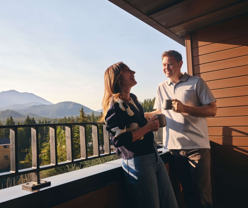 Couple enjoying coffee on a guest room balcony with mountain views at Hotel Alpenrock.