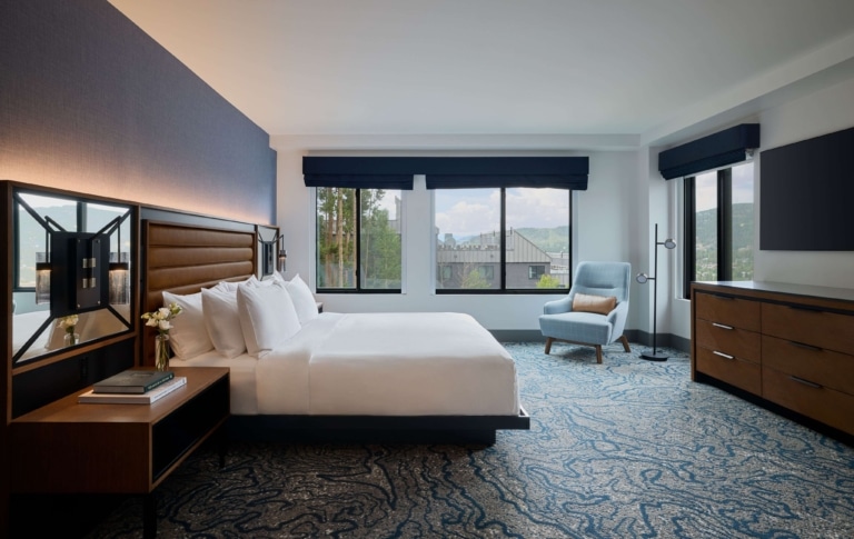 Spacious king suite bedroom with seating area and mountain views at Hotel Alpenrock.