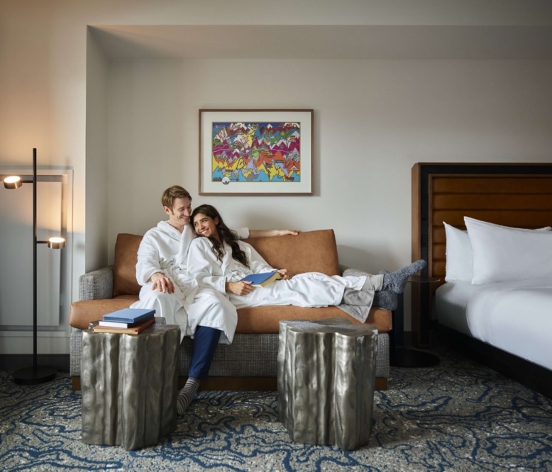 Couple relaxing on a sofa in a Hotel Alpenrock guest room.