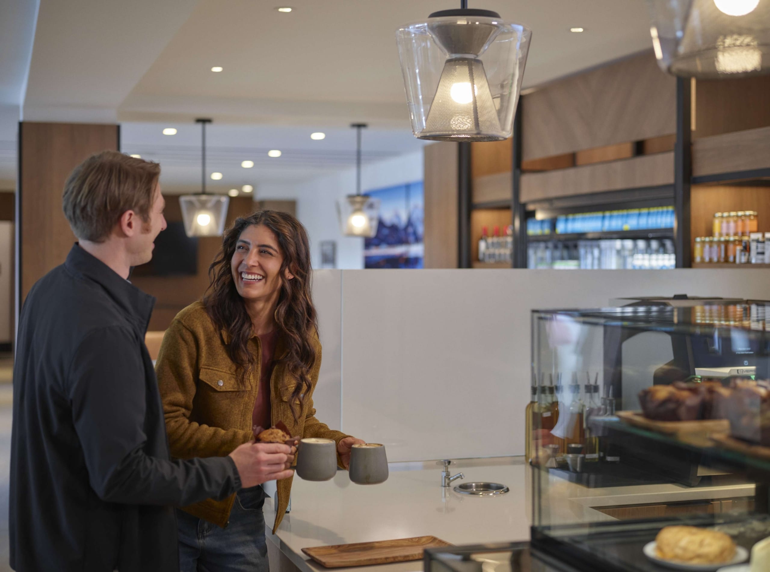 Couple enjoying coffee and pastries together in the Hotel Alpenrock lobby café, surrounded by warm lighting and a modern mountain-inspired interior.