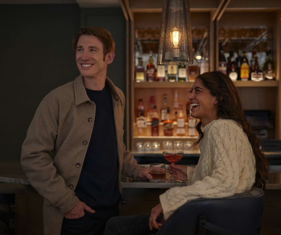 Guests enjoying drinks at the Hotel Alpenrock bar, sharing a relaxed moment under warm pendant lighting in a cozy, modern mountain setting.