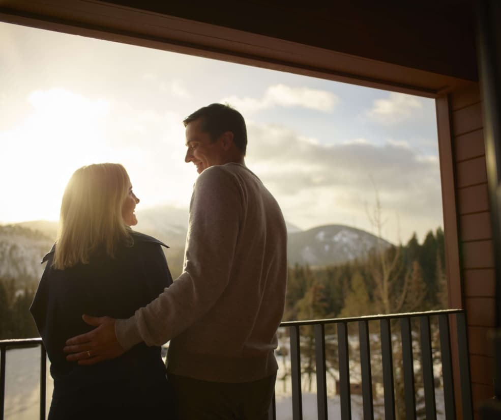 Couple enjoying sunset mountain views from a Hotel Alpenrock balcony.