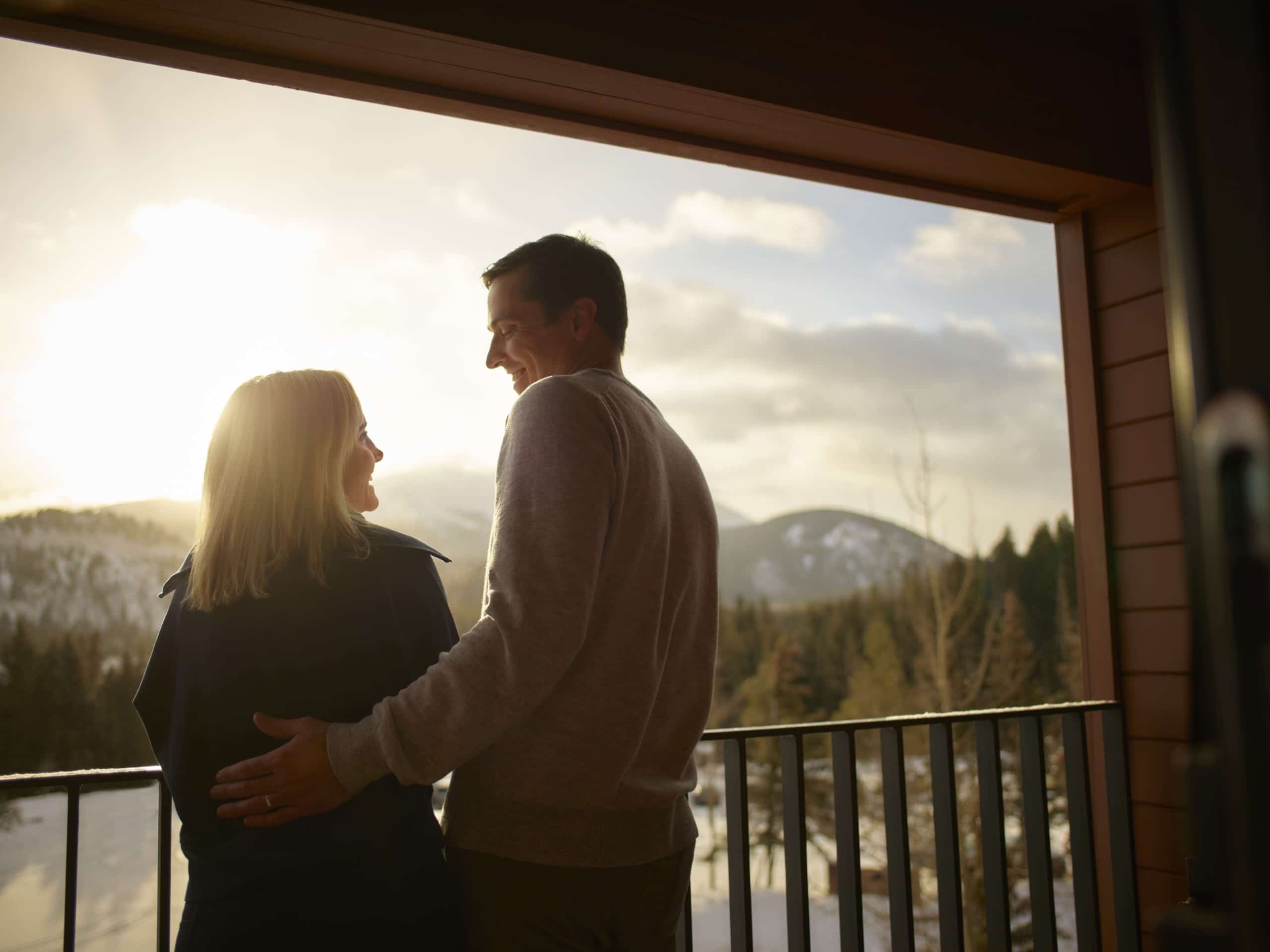 Couple enjoying sunset mountain views from a Hotel Alpenrock balcony.