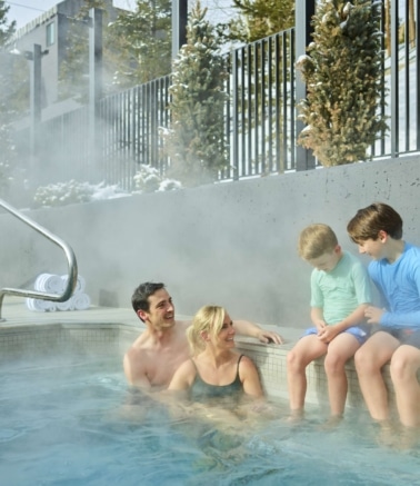 Family enjoying an outdoor hot tub at Hotel Alpenrock.
