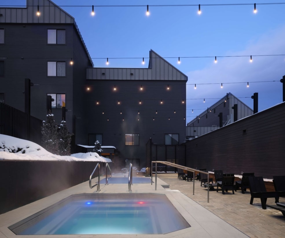 Outdoor hot tubs and seating area at Hotel Alpenrock, illuminated at dusk.